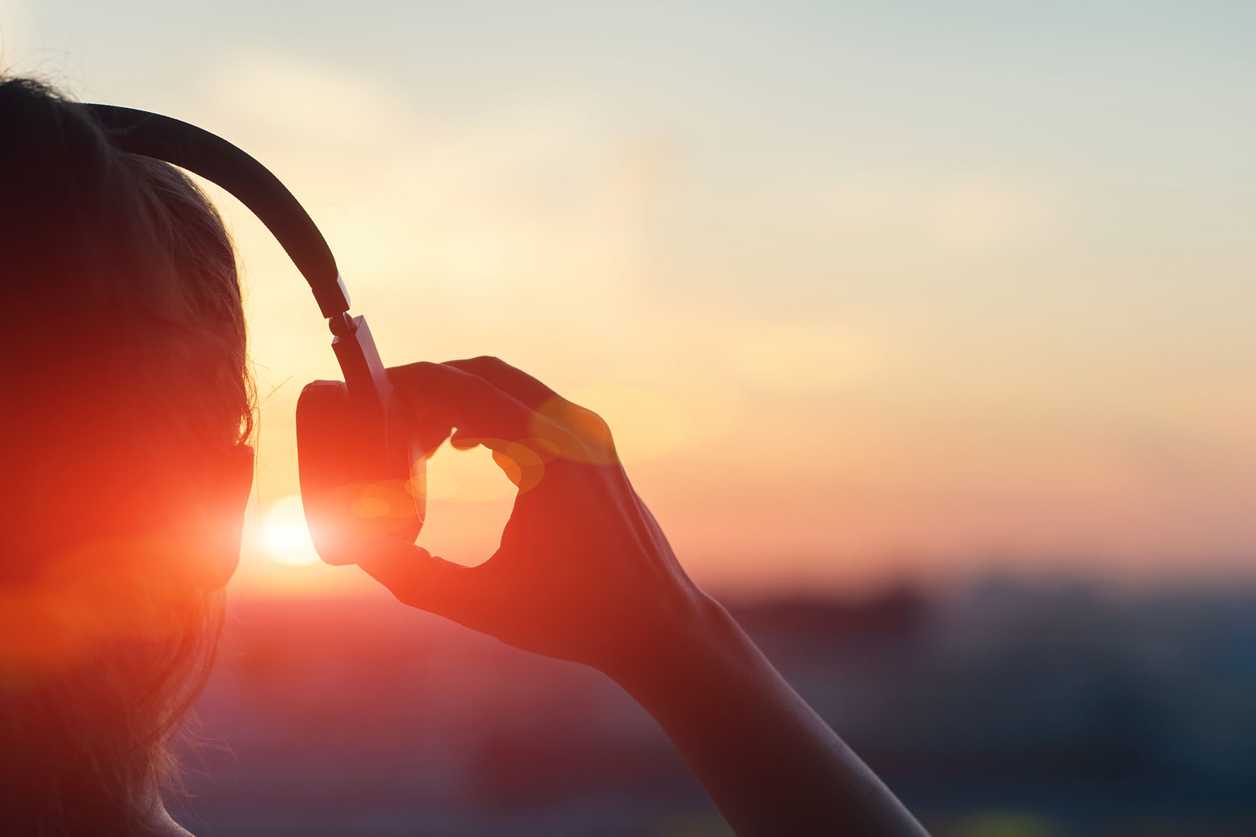 Frau mit Kopfhörern im Sonnenuntergang